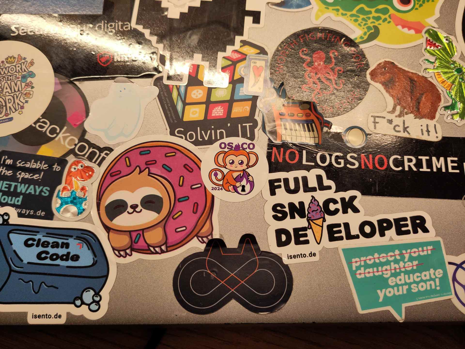 A photo of the laptop lid with many stickers on it. One of them is the osco 2024 sticker.